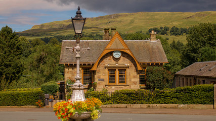 Old station house and ornate lamppost with colourful flowers in Fintry, Scotland