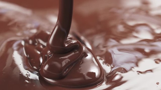 Slow motion pouring premium milk melted chocolate from big spoon