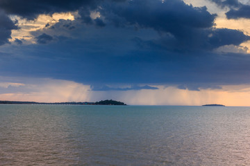 Rain is falling at sunset in the sea.
