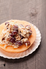 
Cantaloupe ring filled with chicken grape cantaloupe salad on a white plate and dark wooden background vertical shot

