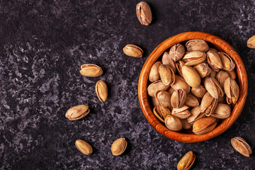 Salted pistachios in a bowl on stone background.
