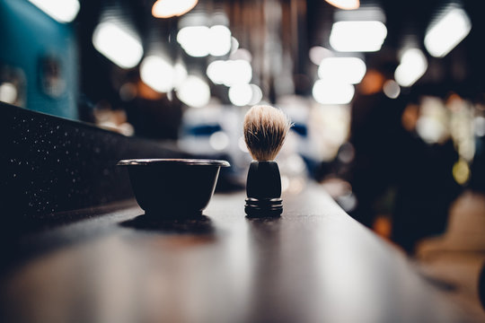 brush for shaving a beard along with a bowl, a blurred background of a hair salon for men, a barber shop