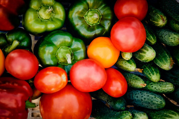 Close-up of farm products in a basket, top view: tomatoes, cucumbers, peppers. Concept is useful products, harvesting.