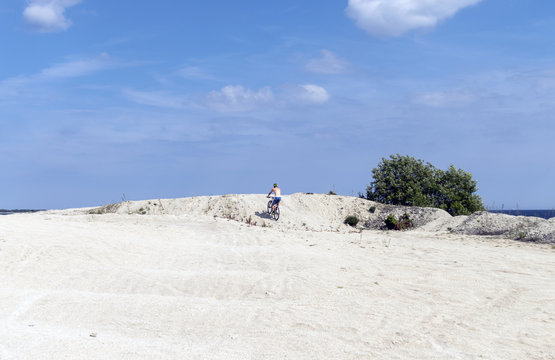 En man tr&auml;nar med en cykel p&aring; stranden