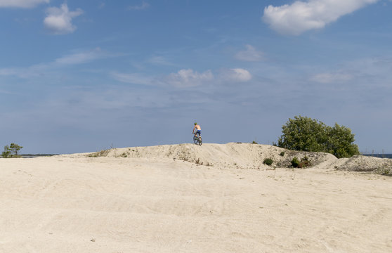 En man tr&auml;nar med en cykel p&aring; stranden