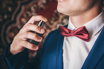 The man sprinkles himself on perfume