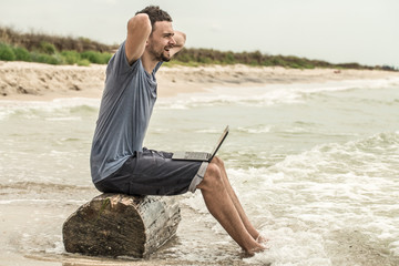 man working with computer on the beach