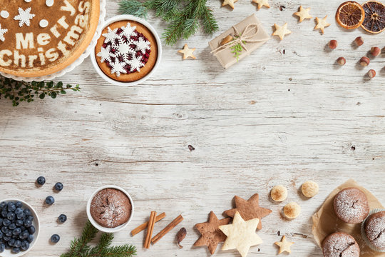 Christmass preparation concept. New Year composition with snowflakes, sweets, cinnamon, on a beige wooden background. Image for greeting card. Top view. Copy space.
