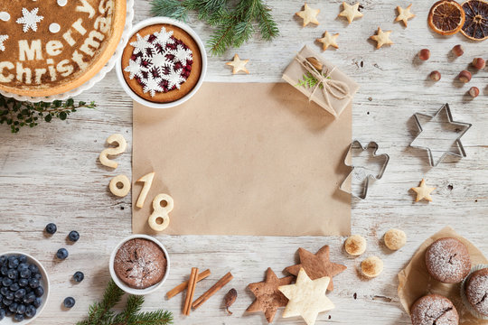 Homemade Christmass cookies, number year 2018, desserts, gift, cinnamon, berries, dried orange, hazelnuts on a beige wooden background. Image for greeting card. Top view. Copy space.