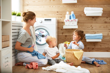 Happy family mother   housewife and children in   laundry load washing machine