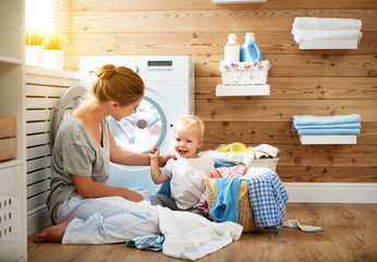 Happy family mother   housewife and children in   laundry load washing machine