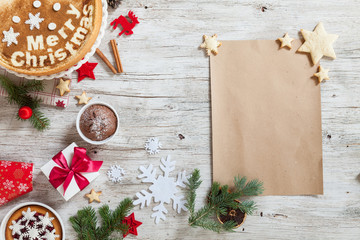 Christmass symbols cake, cinnamon, snowflakes, number year 2018 and empty piece of paper. Christmass background branches of furry spruce, gift on a wooden background. Top view. Copy space.