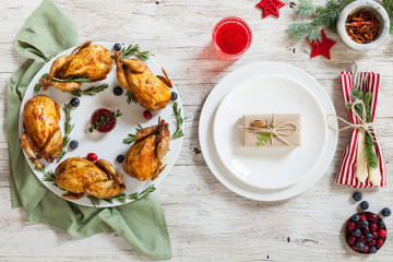 Christmas roast quails served on a holiday table. Festive table served with spice, pepper, berries, furry spruce and little gift. Top view. Spice, pepper, berries and furry spruce on a table.