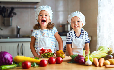 Healthy eating. Happy children prepares  vegetable salad in kitchen