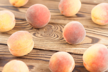 Many scattered fresh whole ripe peaches on old rustic wooden planks