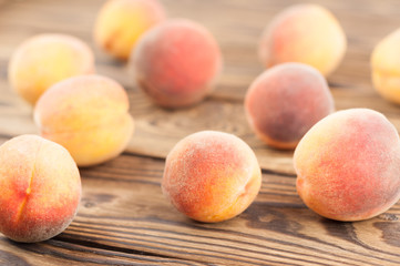 Many scattered fresh whole ripe peaches on old rustic wooden planks