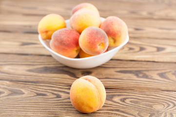 Naklejka na ściany i meble Lot of fresh whole ripe peaches in white ceramic bowl and one peach separately on rustic old wooden planks