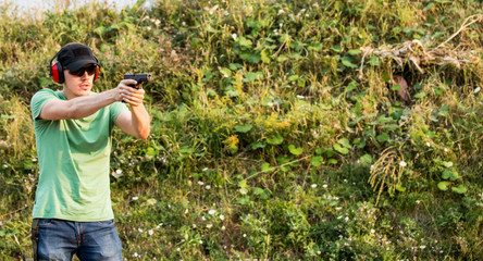 Young and handsome professional policeman special force trained battleground officer shooting with gun  pistol at the enemy target in the wilderness with equipment and protective gear