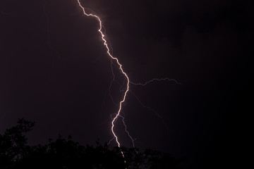 Lighting in the night striking at the ground with sheer force in the storm and clouds in the sky