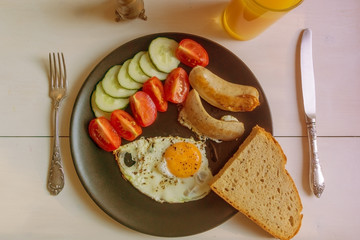 Fried eggs with tomatoes and cucumbers on a rustic wooden background