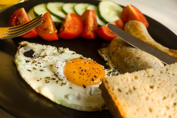 Fried eggs with tomatoes and cucumbers on a rustic wooden background