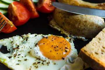Fried eggs with tomatoes and cucumbers on a rustic wooden background