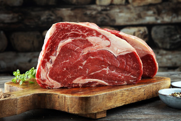 Rohes Frischfleisch Ribeye Steak, Gewürze und Fleischgabel auf dunklem Hintergrund
