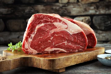 Abwaschbare Fototapete Fleish Rohes Frischfleisch Ribeye Steak, Gewürze und Fleischgabel auf dunklem Hintergrund