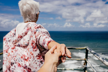 Fototapeta na wymiar .Photograph of mother and daughter leaning on a viewpoint with sea views holding hands unwillingly loosen up on a summer day. Lifestyle portrait.