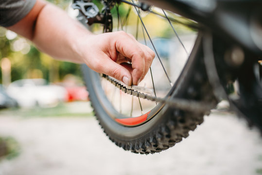 Bicycle mechanic in apron adjusts bike chain