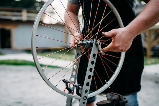 Male person adjusts bike spokes and wheel