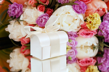 Gift box on a background of a bouquet of flowers