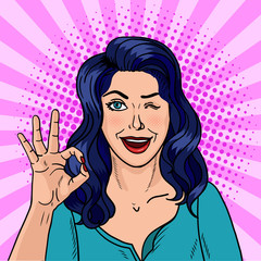 Winking brunette pop art. The black-haired beauty shows with fingers that she is doing well. Vector illustration in comic style.