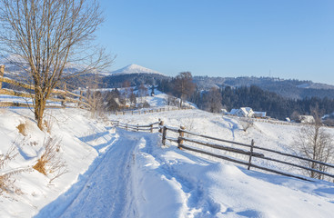 Winter country landscape with timber fence and snowy road