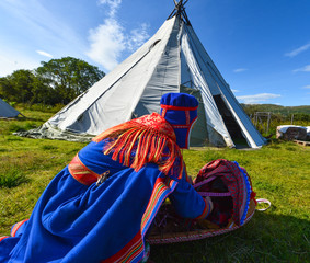 Northern Norway, a traditional dressed Sami woman with a cradle