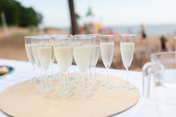 A tray of champagne glasses for the reception on the beach background. Champagne glasses being served on a party