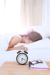 A young woman putting her alarm clock off in the morning.