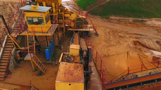Drone view of sand moving on automatic conveyor belt at sand mine. Mining conveyor sorting sand. Mining equipment at quarry. Aerial view sand mining factory line. Mining industry