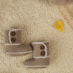 Handmade gift for newborn baby on wintertime, woollen booties, woman hand knitting from ball of yarn, keep warm in cold winter day