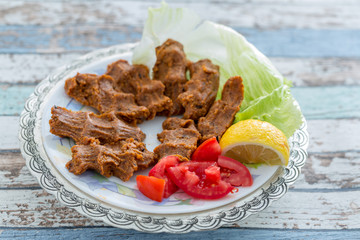 Cigkofte turkish meatball from bulgur with tomato, lemon, and lettuce  side view