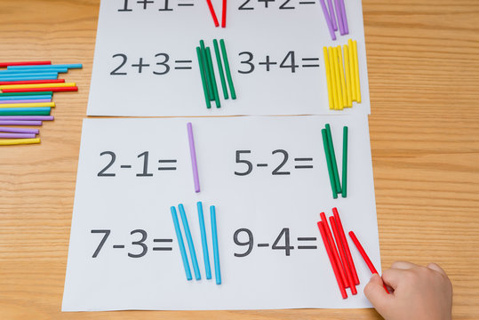 Kid Learning Simple Subtraction And Addition By Counting Numbers Of Sticks