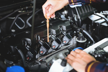 Close up hands checking lube oil level of car engine from deep-stick for service and maintenance concept