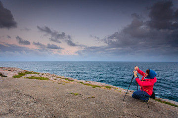 Fototapeta na wymiar Tourist with camera on seashore, Norway