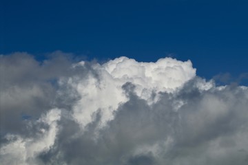 Fototapeta premium Heavy puffy white clouds against a dark azure sky