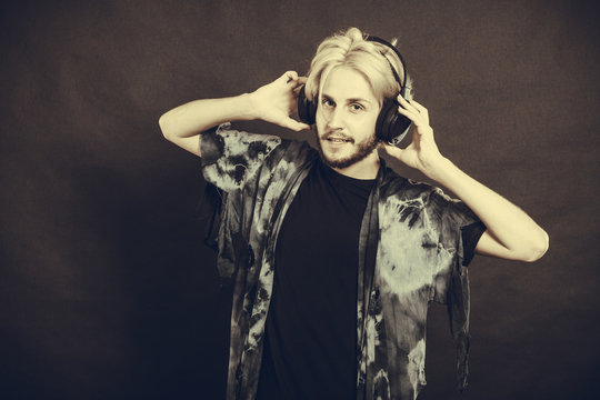 Blonde man singing in studio wearing headphones