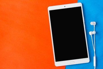 tablet with earphone on orange and blue background