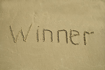 Fototapeta na wymiar On the sand with printed letters the word winner