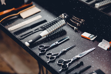 Fototapeta premium Set of tools for barbershop of male hairdresser on dark background: scissors, nozzle for hair clipper, calculation, teeth. Concept abstract background for business.