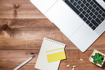 Credit card, laptop, smartphone and coffee cup on wooden table