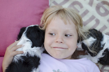Cute laughing girl looking at the camera. Blond 5 years old girl. Ukrainian happy girl. Blonde little girl with puppy. Cute girl lying on back. Cute dog puppy  with girl.